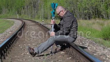 坐在铁路上拄着拐杖的沮丧残疾人